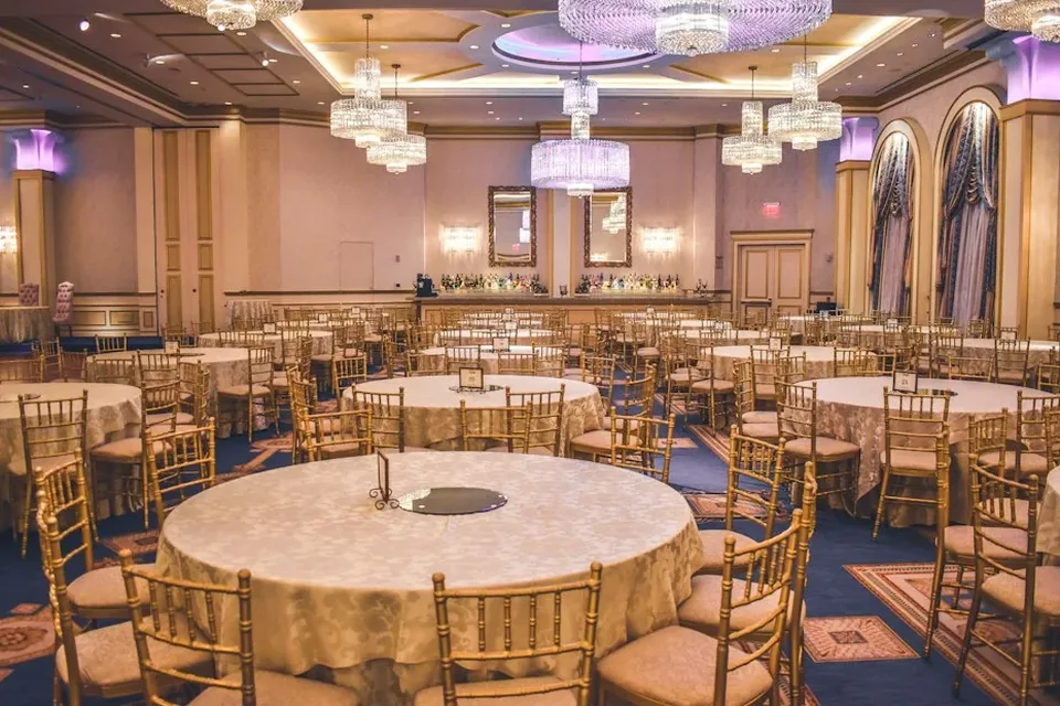 Salón de eventos con mesas montadas y lámparas de cristal